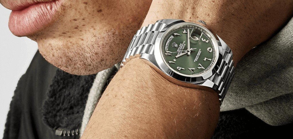 Rolex watch with a green dial and stainless steel bracelet worn on the wrist